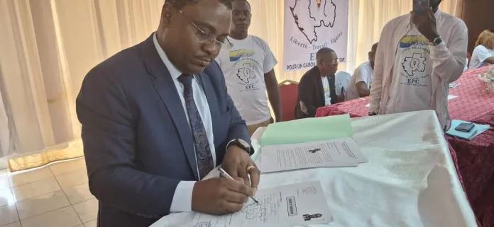 Joseph Lapensée Essingone apposant sa signature sur la fiche d'adhésion lors de la conférence de presse.