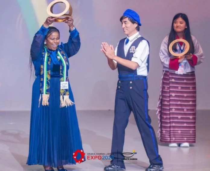 Nina Babouna, responsable de la délégation du Gabon, montrant fièrement le prix obtenu lors de l'Expo 2025 à Osaka.