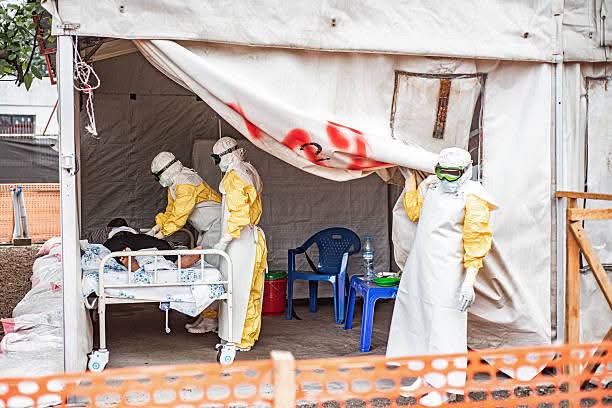 Des agents de santé en équipement de protection interviennent auprès d’un patient dans un centre de traitement Ebola en République Démocratique du Congo.